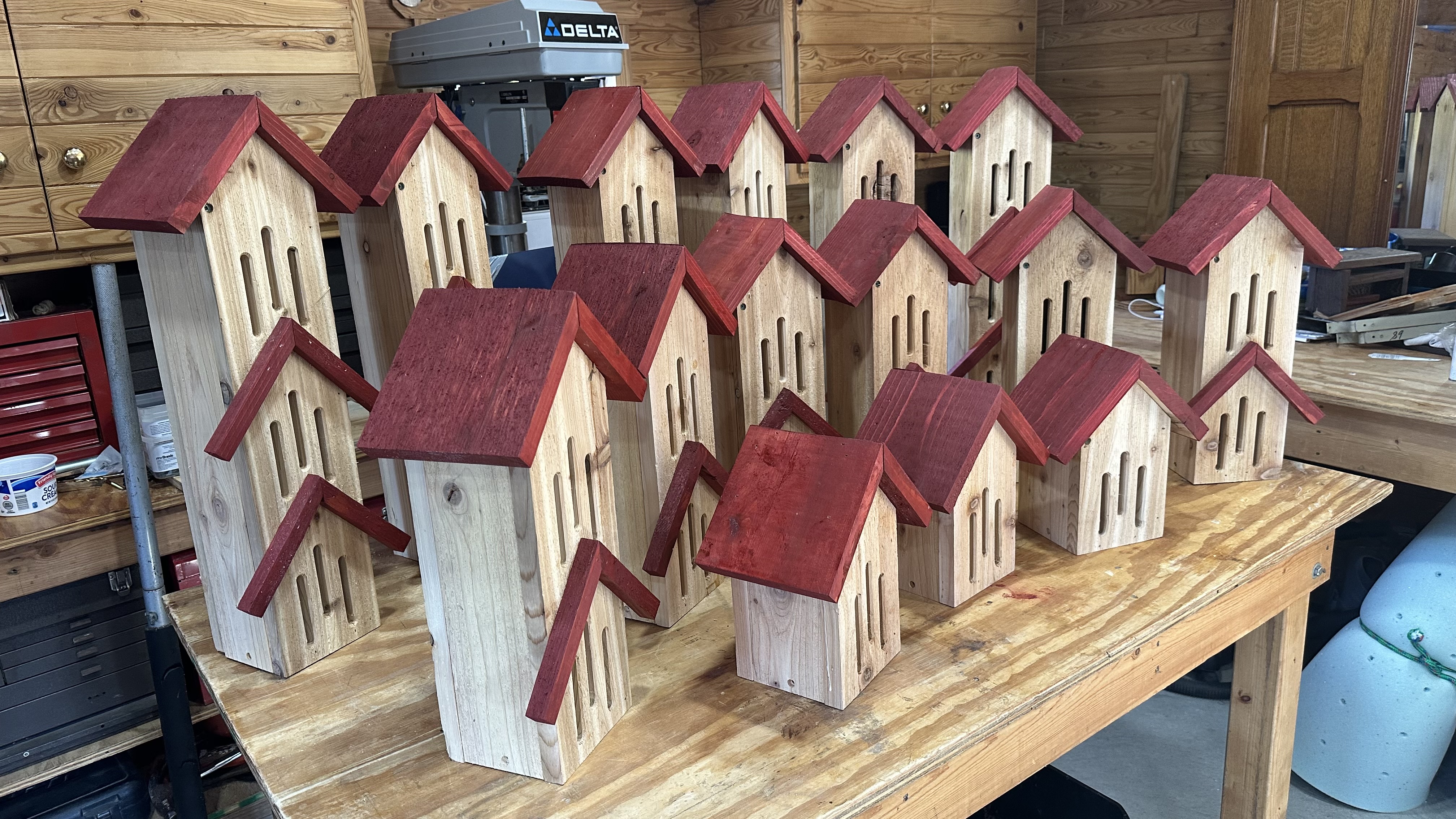 Photo of 15 butterfly houses.  6 3-tier,, 6 two-tear, and three single tier .All made of natural cedar and the roof pieces are red barn stained.   